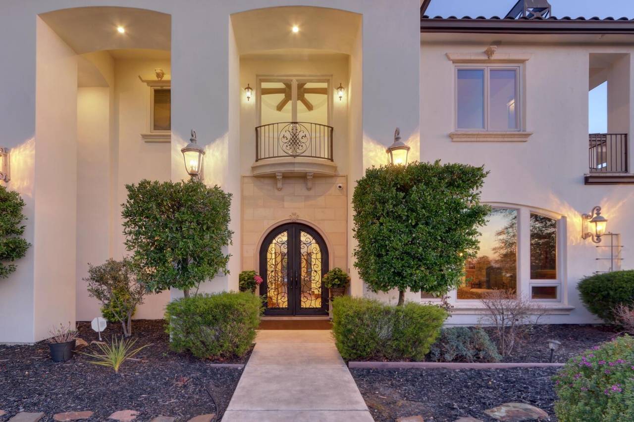The arched front entry, flanked by columns and clipped shrubs
