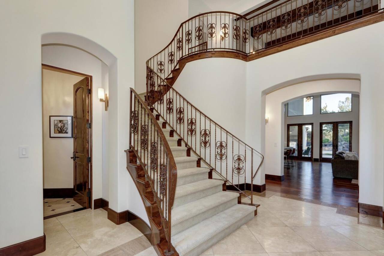 The entry hall, with a curved staircase and a wrought iron balustrade
