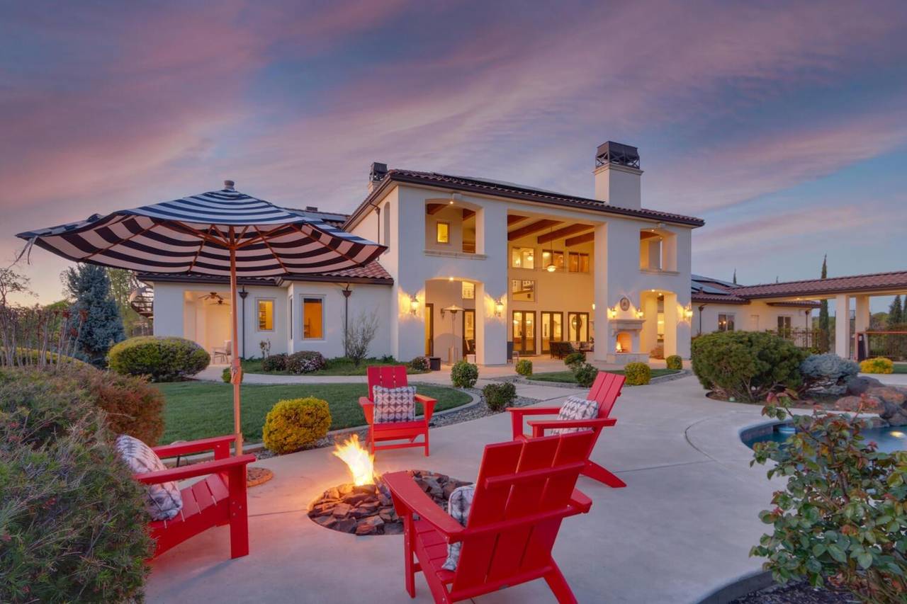 The rear patio at dusk, with red chairs around a fire pit