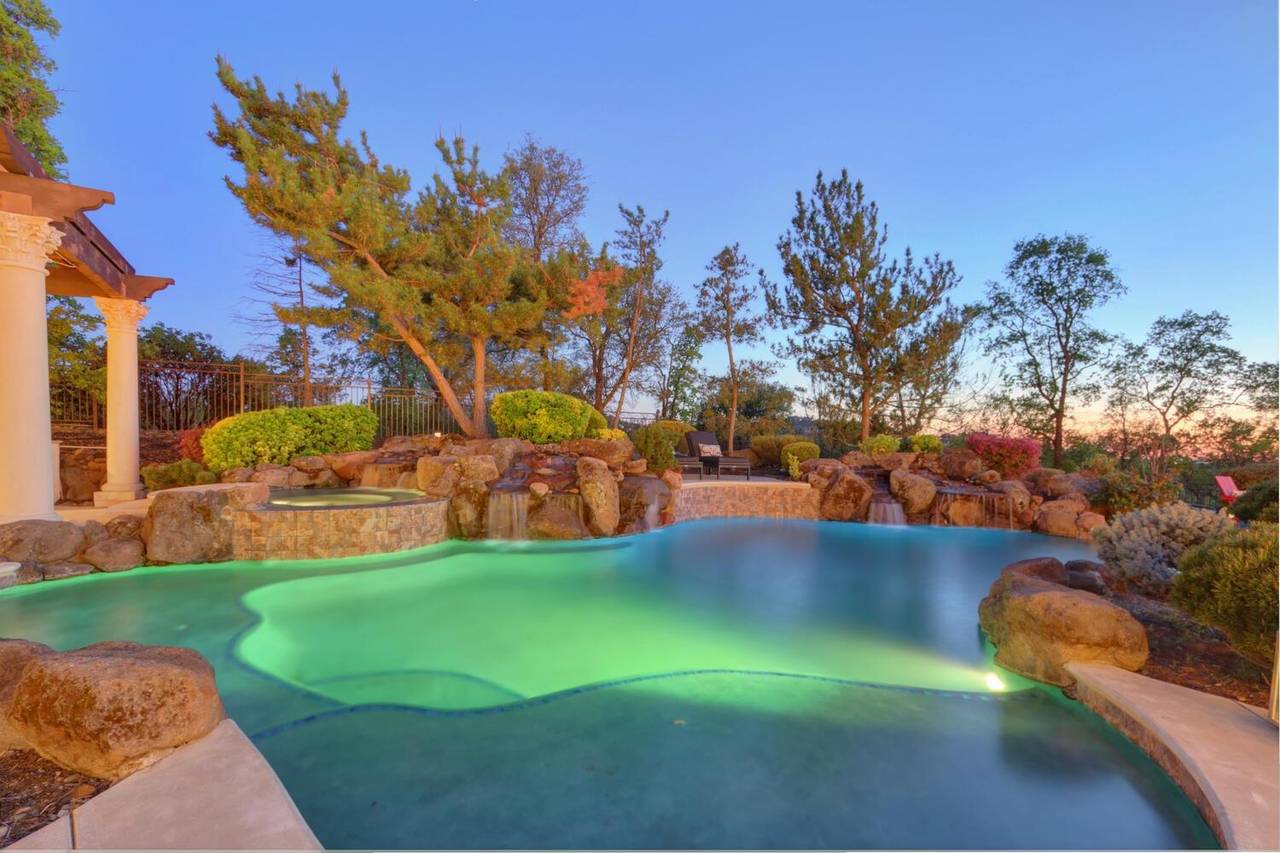 The freeform pool and its rock waterfall, lit at dusk